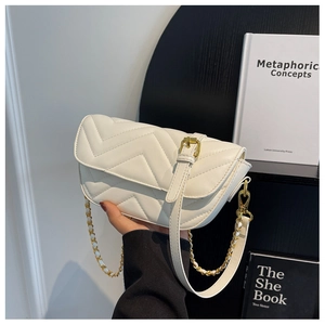 Detail view of a cream-colored chevron quilted leather handbag with gold chain strap