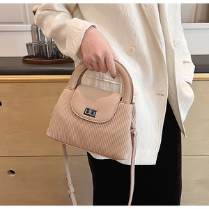 Detailed view of beige pleated crossbody bag with silver square twist lock and handle