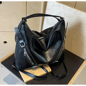 Detail showing glossy black texture and metallic zipper accents on the stylish hobo bag