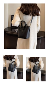 Detail of black lychee grain leather bucket bag with gold lock and thin shoulder strap