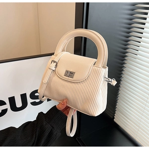 Close-up of off-white lychee pattern leather handbag with metallic rotating lock clasp
