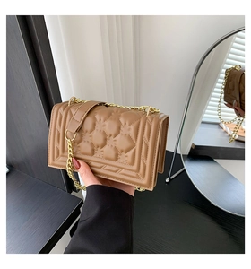 Detail of light brown quilted handbag featuring floral pattern and gold chain strap