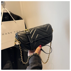 Detail of black quilted leather shoulder bag with gold chain strap and V-shaped stitching