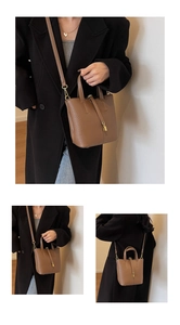 Detail view of dark brown litchi grain leather bucket bag with golden lock clasp