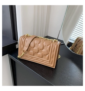 Detail of khaki leather handbag featuring textured quilting and gold chain shoulder strap