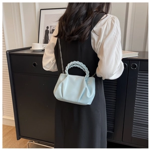 Detailed view of light blue pleated cloud bag with braided handle and silver chain strap