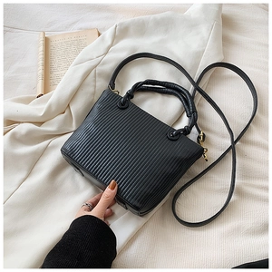 Close-up of vertical pleated texture on black bucket bag with gold-tone hardware
