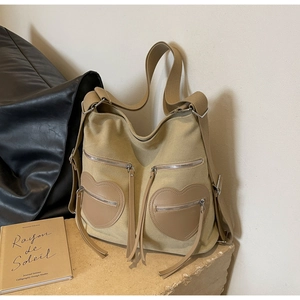 Detail of vintage khaki corduroy backpack with heart-shaped pockets and fringe tassels