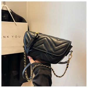 Close-up of black V-quilted leather bag with gold chain strap and strap buckle detail