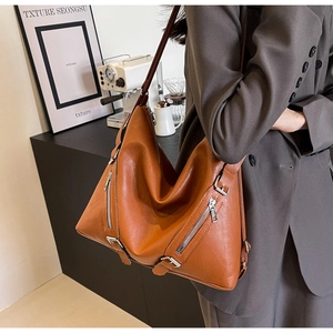 Detailed view of brown leather tote bag with stylish zipper and metal buckle accents