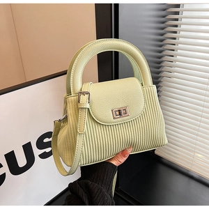 Detail of light green PU leather handbag with vertical embossed stripes and metal twist lock