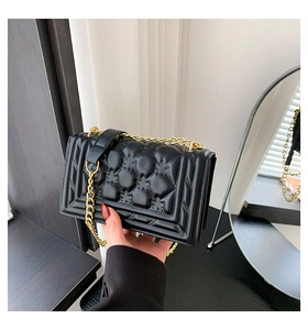 Detailed close-up of black quilted leather handbag with star patterns and gold chain strap