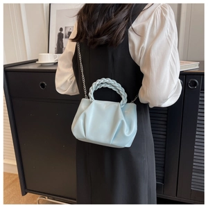 Close-up of a light blue pleated cloud bag with a chunky woven handle and silver chain strap