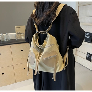 Detail view of beige corduroy backpack with two heart-shaped zipper pockets on model