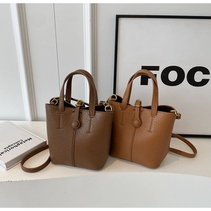 Detailed close-up showing the pebbled leather texture and dual handles of the bucket bag