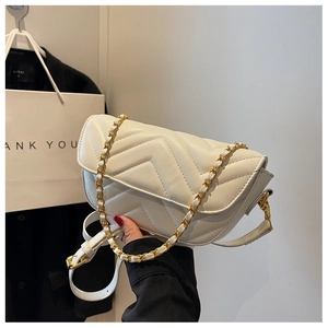 Detail of white V-quilted texture and gold chain strap on the elegant crossbody bag