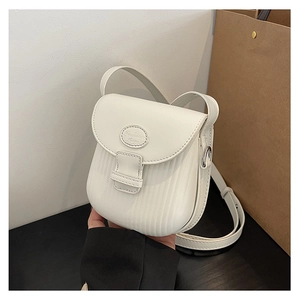 Close-up of white crossbody bag with vertical stripe embossing and metal logo detail