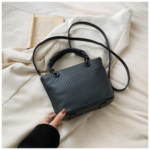 Close-up of black pleated bucket bag with gold metallic lock and vertical striped texture