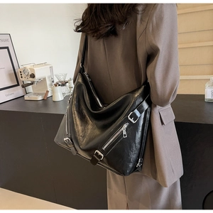 Detail of a large black PU leather tote bag with stylish zipper accents and metal buckles