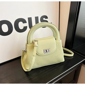 Detail showing vertical striped texture and silver twist lock on the light green handbag
