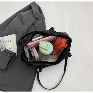 Flat lay of large black tote bag showing spacious interior with tablet and umbrella