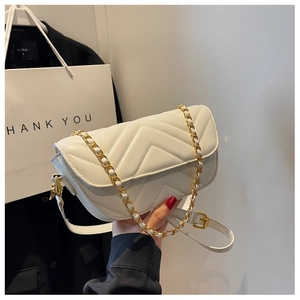 Detail of white V-quilted faux leather crossbody bag with gold chain and metal lock