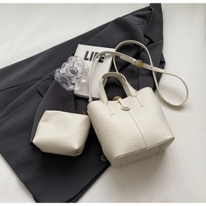 Detail view of cream white bucket bag set with litchi texture and matching zipper pouch