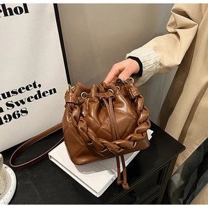 Dettaglio di una borsa a secchiello marrone trapuntata con manico intrecciato e coulisse
