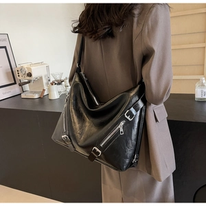 Detail of black large capacity tote bag featuring silver zippers and soft leather texture