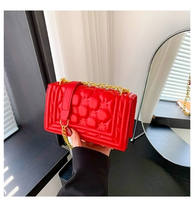 Detailed view of a bright red quilted handbag with golden chain strap and flip cover