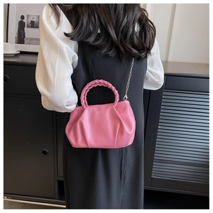 Detail of pink ruched cloud bag with woven handle and silver chain strap on model