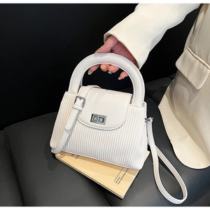 Detail shot of white pleated leather bag with silver metal lock and adjustable shoulder strap