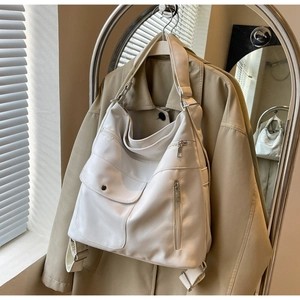 Detail of white PU shoulder bag featuring multi-pocket design and adjustable wide strap