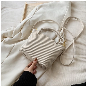 Close-up of cream vertical pleated texture and woven handle on modern bucket bag