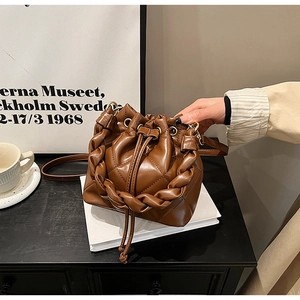 Dettaglio della borsa a secchiello trapuntata caramello con manico intrecciato e coulisse