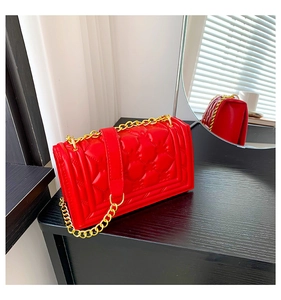 Detail of red quilted PU leather shoulder bag with gold chain strap and square flap