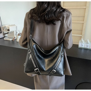 Detail of black PU leather hobo bag with decorative zippers on a model's shoulder
