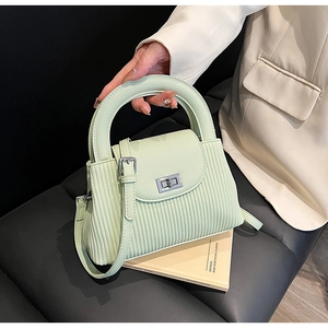 Close-up of mint green pleated PU leather handbag with silver clasp and top handle