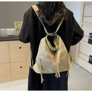 Detail of corduroy backpack featuring heart-shaped leather pocket and long fringe tassels