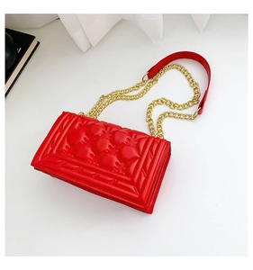 Close-up of red quilted shoulder bag with gold chain strap and elegant rhombus pattern