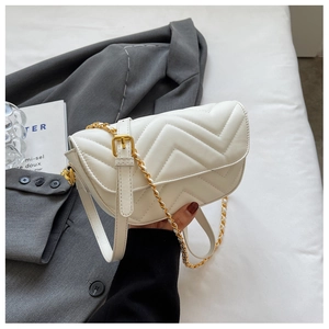 Detail of white quilted crossbody bag with golden chain strap and V-stitch pattern