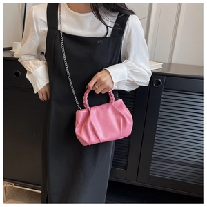 Pink pleated cloud bag with woven handle and silver chain strap shown by a model