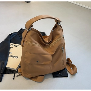 Detail view of large brown tote bag with multiple zipper pockets and wide shoulder strap