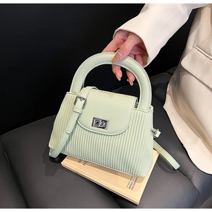 Detail of mint green quilted handbag with vertical stripes and silver square lock