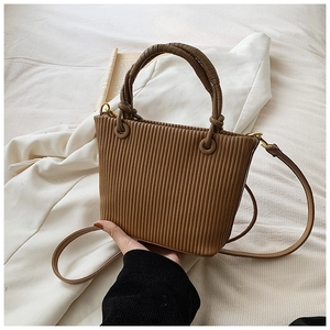 Detail view of vertical pleats and spiral handle on a vintage brown crossbody bucket bag