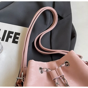 Detail of pink matte leather bucket bag showing drawstring closure and silver eyelets
