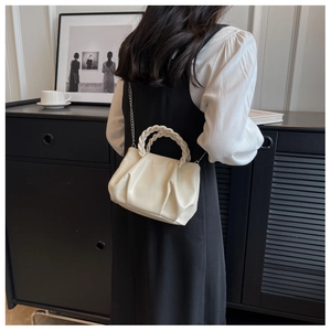 Detailed view of beige pleated cloud bag with woven handle and elegant silver chain strap
