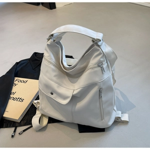Detail view of large white PU leather backpack featuring silver metal zippers and multi-pockets