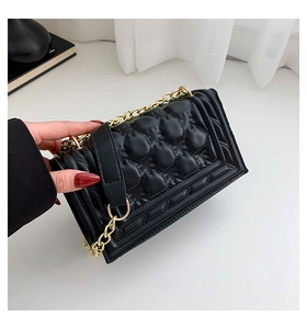 Detail of black quilted leather handbag with elegant gold metal chain and fine stitching
