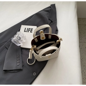 Detailed top view of off-white lychee grain leather bucket bag with inner pouch